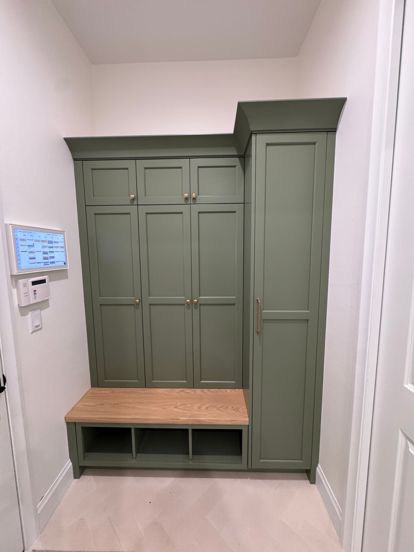Custom sage green mudroom lockers with white oak bench and brass hardware