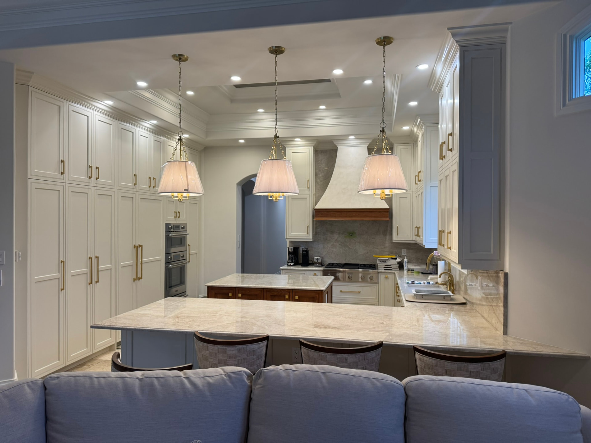 Custom cream kitchen cabinetry with marble countertops, brass hardware, and pendant lighting in a Southwest Florida home
